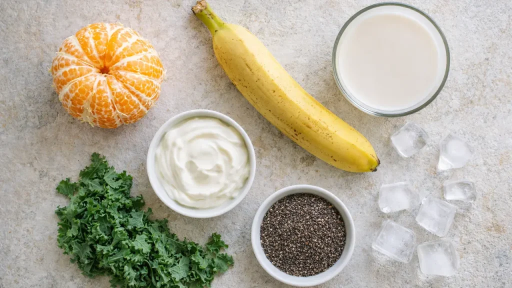 Ingredients for healthy kale orange banana smoothie arranged overhead